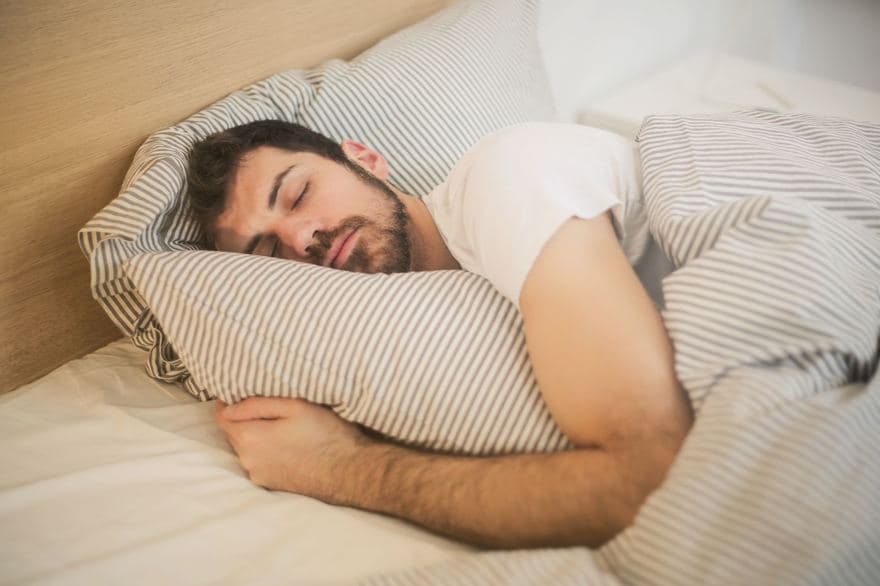Một người đàn ông nằm trên giường, ôm gối ngủ say